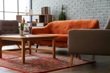 Eski halı, kanepe ve koltukları olan rahat bir oturma odası.