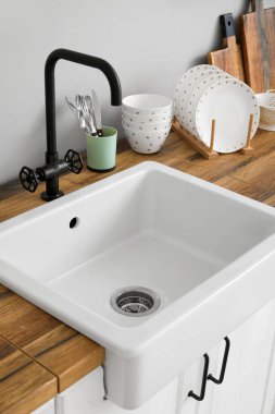 Seramik lavabolu ahşap tezgah ve ışık duvarının yanında mutfak aletleri.