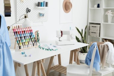 Atölyede dikiş makinesi ve iplik makaralarıyla modern terzinin işyeri