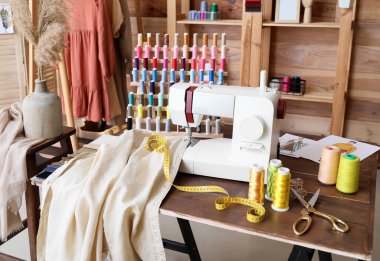 Atölyede dikiş makinesi, giysi ve iplik makaralı terzinin işyeri