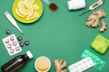 Boğaz ağrısı, limon dilimleri, zencefil ve yeşil arka planda termometreler için kullanılan ilaçlardan yapılmış çerçeve.