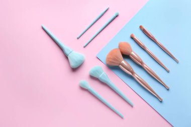 Mavi ve pembe arkaplanda makyaj fırçaları, üst görünüm
