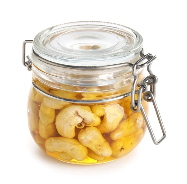 Beyaz arka planda ballı bir kavanoz lezzetli kaju fıstığı.