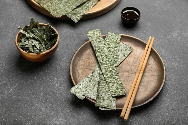 Lezzetli bir tabak yosun ve siyah arka planda soya soslu bir kase.