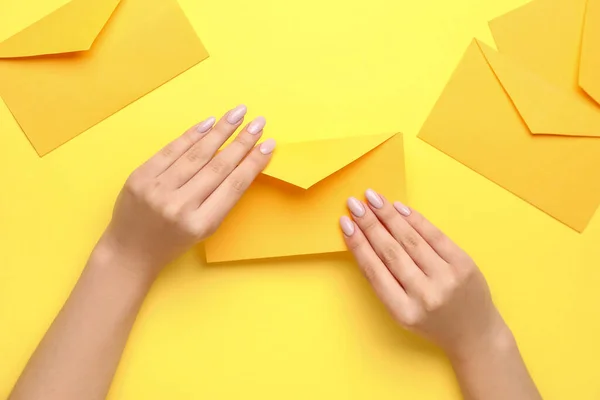 Sarı Arka Planda Güzel Manikürlü Zarflı Kadın Elleri — Stok fotoğraf