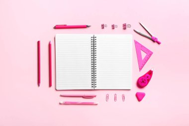 Pembe arkaplanda boş defter ve kırtasiye malzemesi