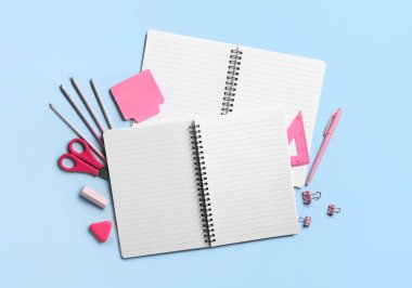 Mavi arkaplanda boş defterler ve kırtasiye malzemesi