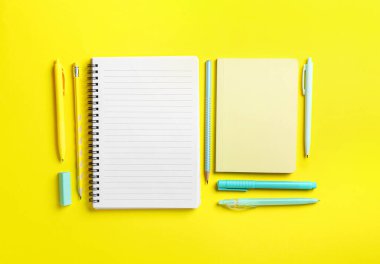 Sarı arkaplanda boş defterler ve kırtasiye malzemesi