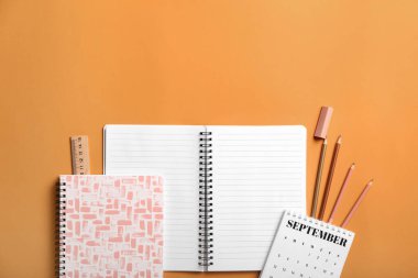 Turuncu arkaplanda boş defter ve kırtasiye malzemesi