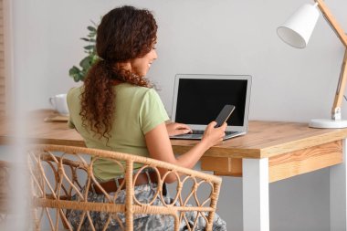 Evde dizüstü bilgisayarı olan Afro-Amerikalı kadın asker.