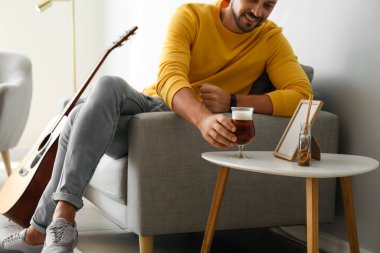 Yakışıklı adam evde bira içiyor.