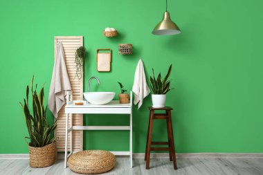 Beyaz masası, lavabosu ve çiçekleri olan şık bir banyo.