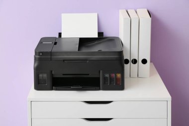 Renk duvarı yakınında yazıcı ve dizinleri olan çekmece sandığı