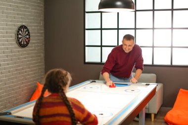 Babası ve küçük kızı içeride hokey oynuyorlar.