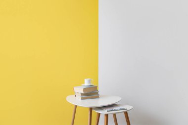 Renkli duvarın yanında kitapları ve dergisi olan modern masalar.