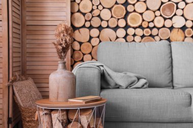 Modern masa, sazlık çiçekli vazo ve odanın içindeki kanepe.