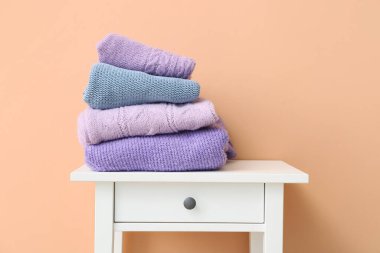 Renkli duvarın yanındaki masada örülmüş süveterler.