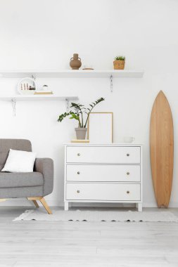 Tahta sörf tahtası, tuvalet ve raflarla aydınlık oturma odasının içinde.