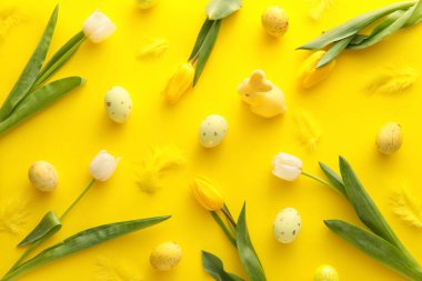 Boyalı Paskalya yumurtaları, lale çiçekleri ve sarı arka planda tüyler.