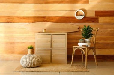 Ahşap sörf tahtası, klozeti ve sandalyesi olan şık bir oda.