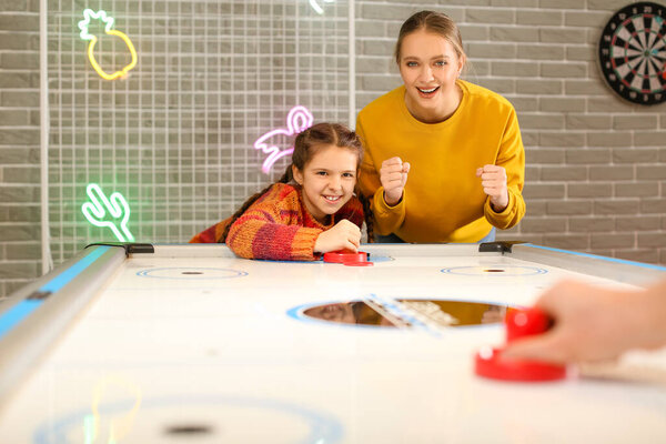Family playing air hockey indoors