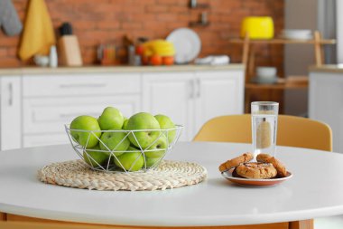 Mutfaktaki masada taze elma, kurabiye ve bir bardak su.