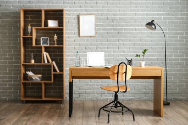 Modern dizüstü bilgisayarlı rahat bir iş yeri, ofiste bir şişe su ve cam.