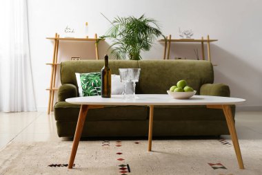 Oturma odasında şarap, bardak ve elma dolu bir masa.