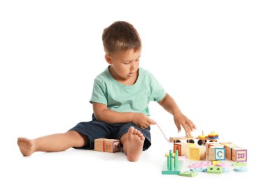 Beyaz arka planda tahta oyuncaklarla oynayan sevimli küçük çocuk.