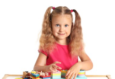 Beyaz arka plandaki masada yapı taşlarıyla oynayan sevimli küçük kız.