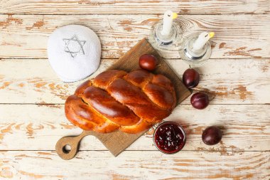 Beyaz ahşap arka planda parlak mumları ve Yahudi şapkası olan geleneksel challah ekmeği. Şabat Şalom