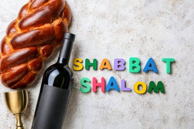 Şarap şişeli geleneksel challah ekmeği ve grunge arkaplan üzerinde SHABBAT SHALOM metin