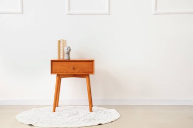 Kitap ve dekorasyonlu ahşap komodin, ışık duvarı yanında.