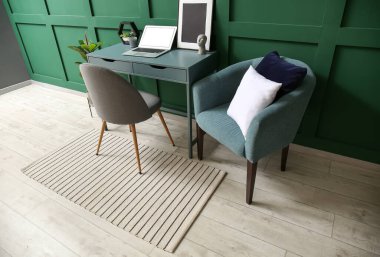 Renkli duvarın yanında rahat koltuğu ve modern çalışma yeri olan bir oda.