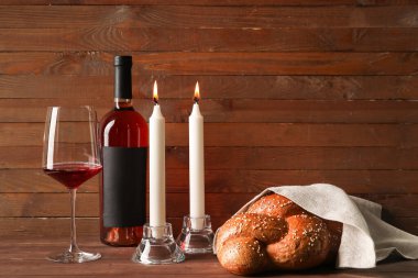 Şarap ve ahşap arka planda parlayan mumlarla geleneksel challah ekmeği. Şabat Şalom