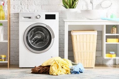 Çamaşır odasında çamaşır makinesinin yanında kirli çamaşırlar var.