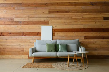 Odanın içinde kanepe, masa ve boş fotoğraf çerçevesi olan ahşap duvarın yanında.