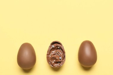 Sarı arka planda yapıştırıcılı lezzetli çikolata yumurtaları.