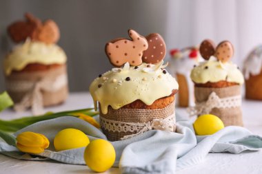 Kurabiyelerle süslenmiş lezzetli Paskalya pastaları ve masadaki boyalı yumurtalar, yakın plan.