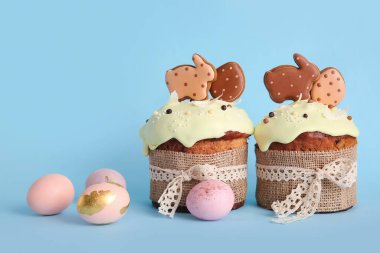 Kurabiyelerle süslenmiş lezzetli Paskalya pastaları ve mavi arka planda boyanmış yumurtalar.