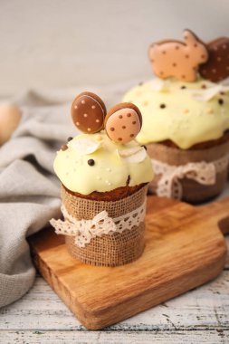 Hafif arka planda kurabiyelerle süslenmiş lezzetli Paskalya pastalarıyla dolu tahta.