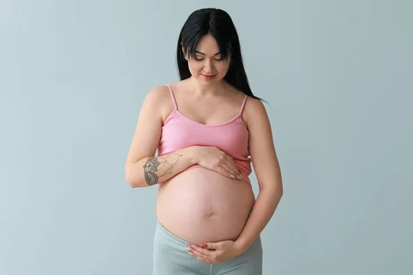灰色の背景に妊娠中の若い女性 — ストック写真