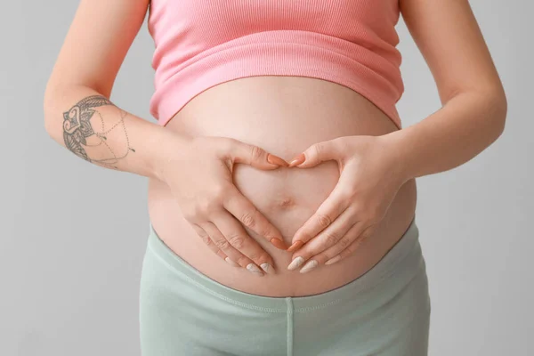 Kobieta Ciąży Kształtuje Serce Dłońmi Brzuchu Szarym Tle Zbliżenie — Zdjęcie stockowe