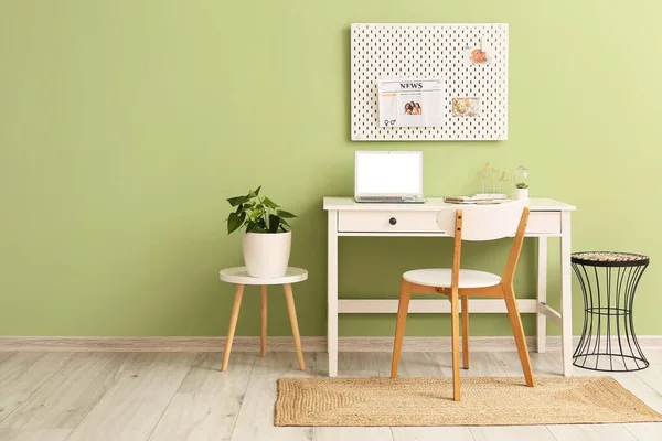 Yeşil duvarda farklı malzemeler ve tahta olan modern işyeri.