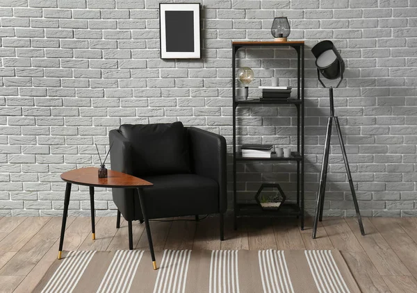 Szoba Belseje Kényelmes Fotellel Polccal Modern Szőnyeggel Szürke Téglafal Közelében — Stock Fotó