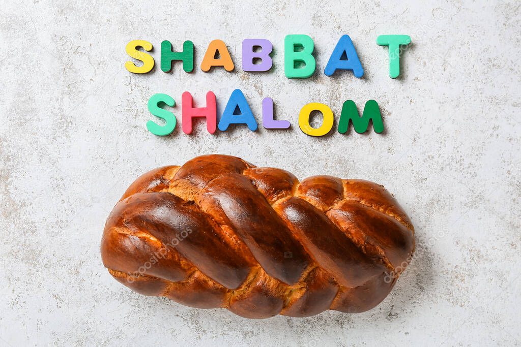 Traditional challah bread and text SHABBAT SHALOM on grunge background