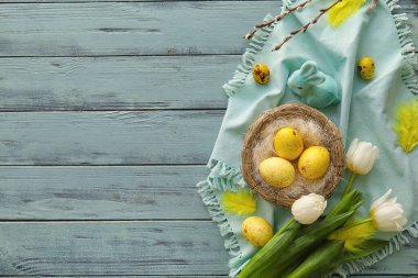 Renkli ahşap arka planda boyanmış Paskalya yumurtaları, tavşan ve lale çiçekleriyle kompozisyon