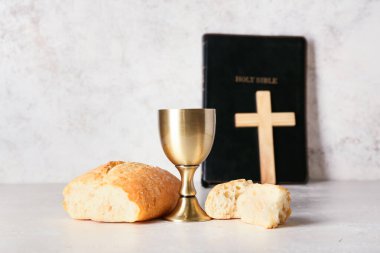 Ekmekli şarap, kutsal kitap ve arka planda haç.