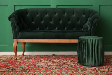 Yeşil duvarın yanında puf ve antika halılı kanepe