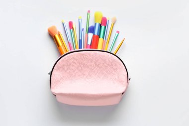 Renkli makyaj fırçalarının olduğu çanta beyaza izole edilmiş.